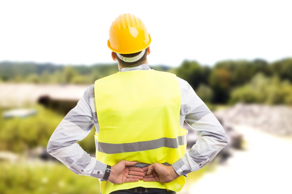 Injured construction worker or engineer suffering backpain in lower back area outdoor at work